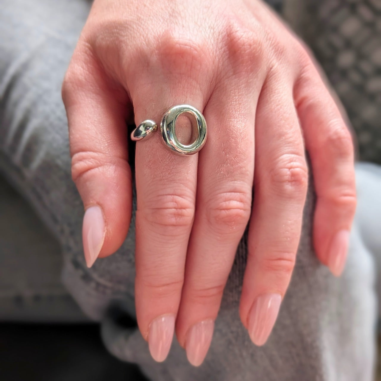 The Lana Ring by Bellagio & Co. Close-up of a hand wearing a 925 sterling silver ring  with a unique circular design. Worldwide shipping.