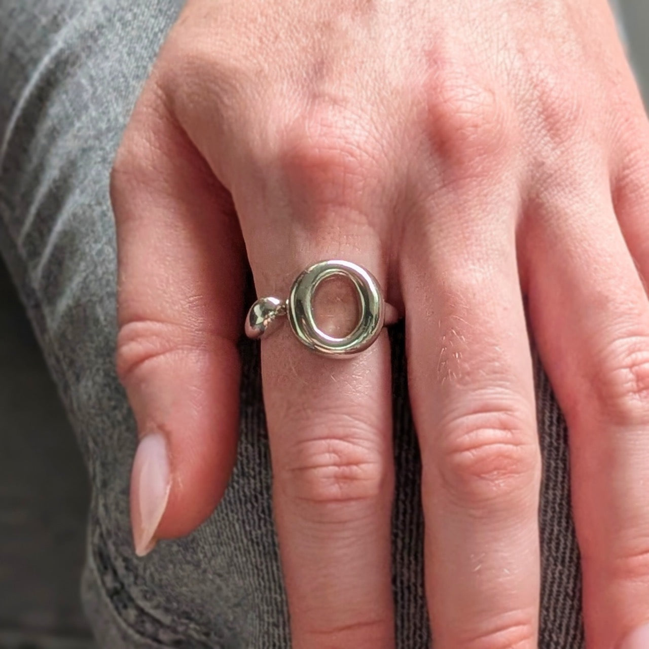Close-up of a hand wearing a 925 sterling silver ring  with a unique circular design. The Lana Ring by Bellagio & Co. Worldwide shipping.