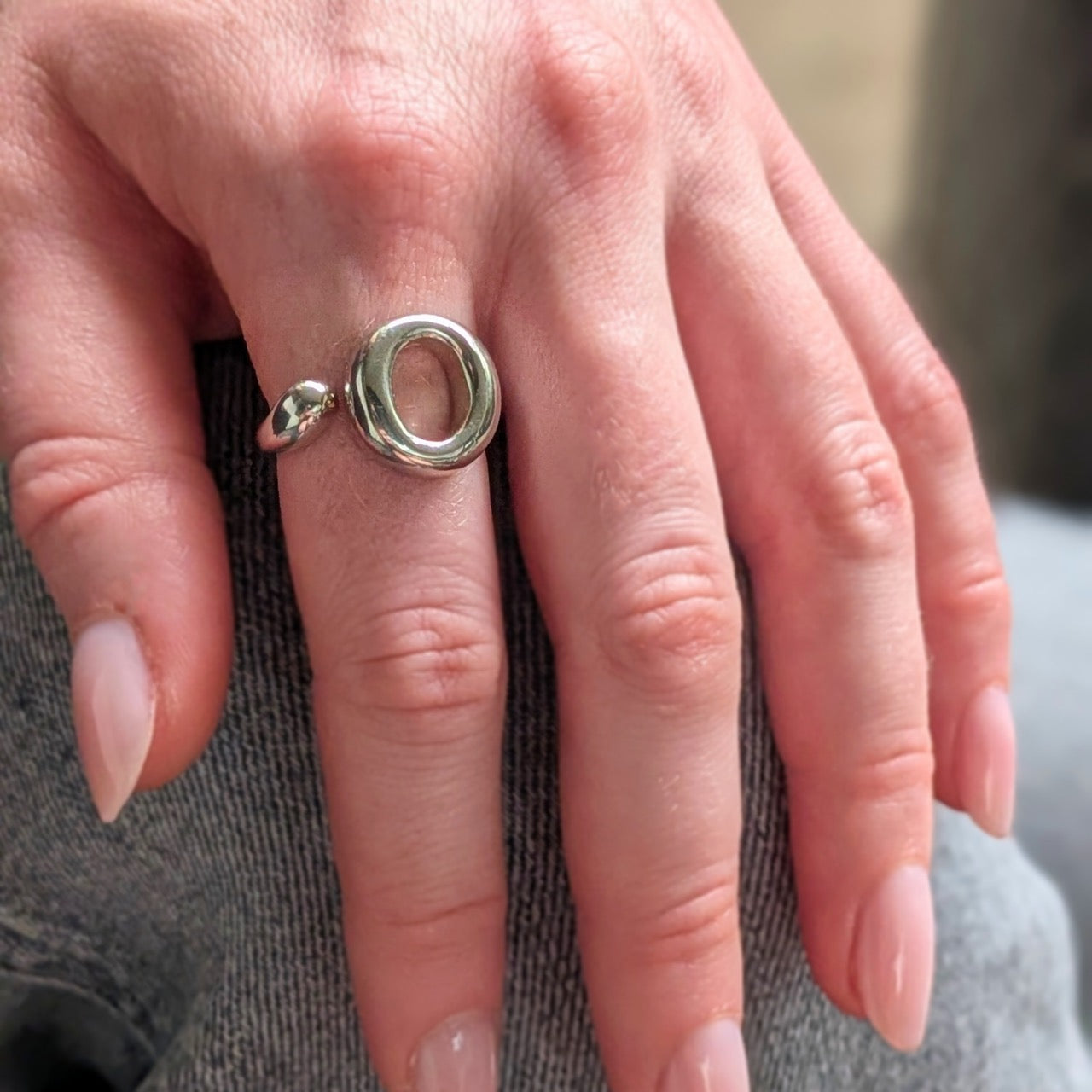 Close-up of a hand wearing a 925 sterling silver ring  with a unique circular design. The Lana Ring by Bellagio & Co. Worldwide shipping.