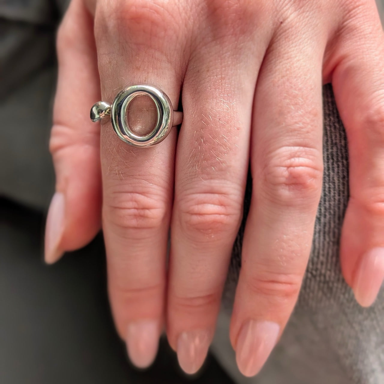 Close-up of a hand wearing a 925 sterling silver ring  with a unique round design. The Lana Ring by Bellagio & Co. Worldwide shipping.