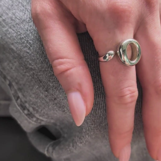 The Lana Ring by Bellagio & Co. Close-up of a hand holding a glass of rose and wearing a 925 sterling silver ring  with a unique circular design. Shop online. Worldwide shipping.